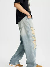 Men’s full size distressed wide leg jeans in light-wash denim with frayed patches along the outer leg
