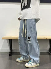 Men’s light-wash denim full size distressed wide leg jeans with ripped details and drawstring waistband