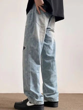 Men’s light-wash denim full size distressed wide leg jeans with subtle paisley pattern and distressed details
