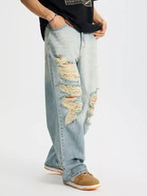 Men’s full size distressed wide leg light-wash denim jeans with prominent frayed ripped patches on thigh and knee