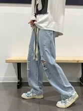 Men’s light-wash denim full size distressed wide leg jeans with ripped details and frayed drawstring waistband