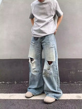 Men’s full size distressed wide-leg jeans in faded light blue denim with ripped knees and a relaxed fit