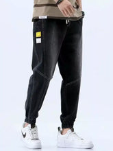 Men’s black denim joggers with white stitching and yellow label featuring a size drawstring loose fit design