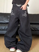 Back view of men’s black denim full size embroidered wide leg jeans with white swirl designs on back pockets
