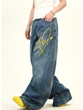 Men’s blue denim love washed wide leg jeans with yellow love x embroidery and paint-splatter details plus size