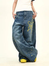 Men’s full size love washed wide leg jeans in blue denim with yellow graffiti style lettering and paint splatter details