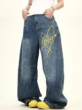 Men’s blue denim love washed wide leg jeans with yellow love x graphic and paint splatter details plus size