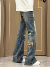 Men’s blue denim wide-leg jeans with distressed patchwork and colorful embroidery for everyday wear in plus size