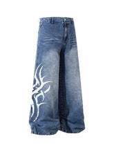 Men’s blue denim wide-leg jeans in a fabric blend featuring a bold white tribal-style graphic on the left leg