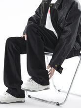 Men’s full size relaxed fit jeans paired with a black leather jacket featuring gold-tone buttons and zipper closure