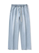 Men’s light-wash denim joggers with elastic waistband and white drawstrings in a relaxed fit wide leg style