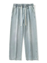 Men’s light-wash denim jogger pants with elastic waistband and white drawstrings in relaxed fit wide leg style