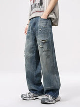 Men’s full size vintage distressed blue denim jeans with relaxed fit wide leg and intentional rips and frayed edges