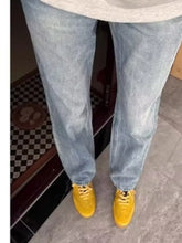 Men’s full size vintage wash straight leg jeans in light wash denim paired with bright yellow sneakers