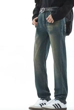 Men’s full size vintage wash straight leg dark-wash denim jeans with faded distressing paired with black belt and white sneakers