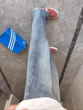 Men’s full size vintage wash straight leg jeans in light-wash denim paired with red and white sneakers