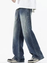 Men’s dark blue denim jeans with relaxed wide leg cut and white drawstrings featuring vintage wash wide design