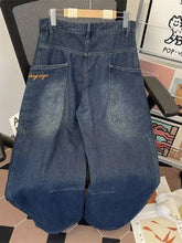 Men’s full size vintage wash wide leg jeans in dark blue denim with orange embroidery on back pocket shown from back side