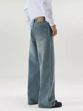 Men’s full size vintage wash wide-leg jeans in faded blue denim with subtle distressing and brown leather patch waistband