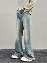 Men’s full size vintage wash wide leg jeans in faded blue denim with subtle yellowish distressing along the legs