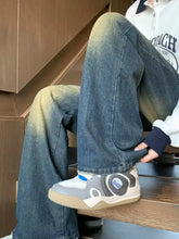 Men’s full size vintage wash wide leg jeans paired with gray and white athletic sneaker with blue accent stripe and logo