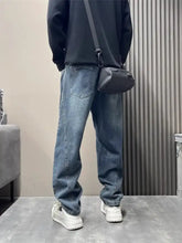Black crossbody bag with sleek minimalist design and adjustable strap paired with men’s full size wash loose fit jeans