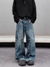 Men’s full size washed wide leg jeans in medium-wash blue denim with visible stitching and patchwork details