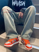 Bright orange and white nike dunk low sneakers with red laces paired with men’s full size washed wide leg jeans