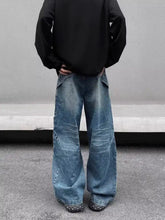 Men’s full size washed wide leg jeans in medium-wash denim with visible stitching and patchwork details