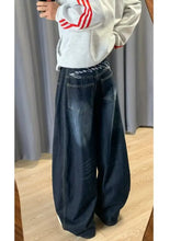Men’s dark blue wide leg barrel jeans with faded wash and white embroidered text on the waistband