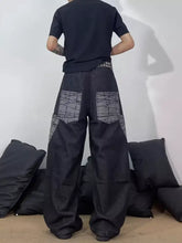 Men’s full size wide-leg cargo jeans in black showing the back with geometric gray patchwork on cargo pockets