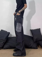 Men’s full size wide-leg cargo jeans in black denim with a distinctive gray geometric patch on the thigh