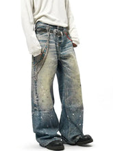 Men’s washed denim wide leg jeans with distressed paint splatter design and metallic chain accents plus size
