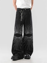 Men’s full size black wide leg denim jeans with bold white rhinestone sunburst patterns on the thighs