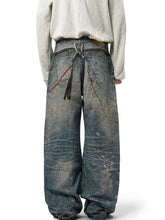 Men’s full size wide leg jeans in faded blue denim with distressed details and decorative beaded chains on back pockets