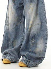 Men’s full size wide leg jeans in faded blue denim with distressed patches and subtle yellow stains