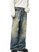 Men’s full size wide leg jeans in washed denim with faded blue and beige paint splatter and a silver belt buckle