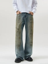 Men’s full size wide leg relaxed fit jeans in faded blue denim with distressed mottled greenish brown patches