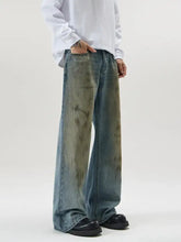 Men’s full size wide leg relaxed fit jeans in faded blue denim with distressed olive green tie-dye patterns