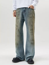 Men’s full size wide leg relaxed fit jeans in faded blue denim with darker brownish gray distressed patches