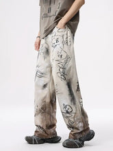 Beige distressed men’s wide leg jeans with faded wash and black graffiti print wide markings