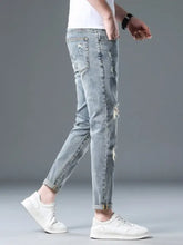 Men’s plus size distressed slim fit jeans in light-wash denim with slight stretch, ripped details, and rolled cuffs