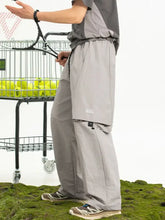 Man in mens plus size drawstring pants holds tennis racket by ball cart