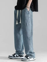 Men’s plus size loose fit drawstring jeans in light-wash denim with white drawstrings and a relaxed tapered fit