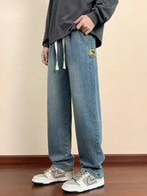 Men’s plus size relaxed fit jeans in light-wash denim jogger style with drawstring waist and yellow thigh patch