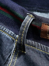 Men’s plus size dark blue denim relaxed fit jeans with yellow stitching and colorful striped waistband detail