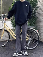 Men’s plus size relaxed fit straight leg jeans paired with a black oversized sweatshirt featuring a white chest patch