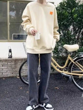 Cream-colored oversized sweatshirt with small orange patch paired with men’s plus size relaxed fit straight leg jeans