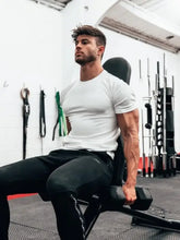 Muscular man in plus size short sleeve athletic t-shirt holding dumbbell