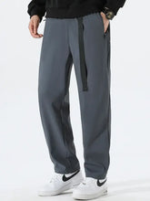Man in plus size solid loose fit pants: baggy gray with black strap, white sneakers